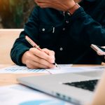 Businessman holding pen and pointing paper chart summary analyzi